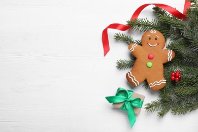 Flat lay composition with gingerbread man and Christmas decor on white wooden table, space for text