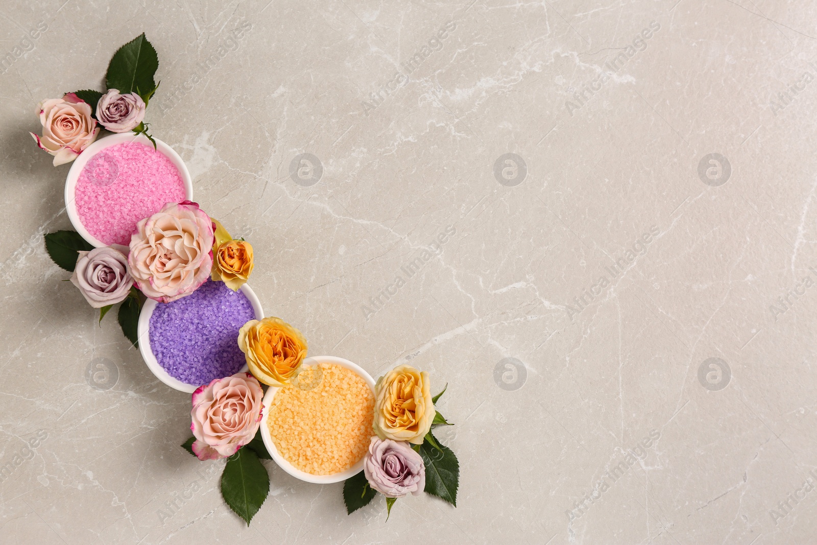 Photo of Bowls with different sea salt and beautiful roses on light marble table, flat lay. Space for text