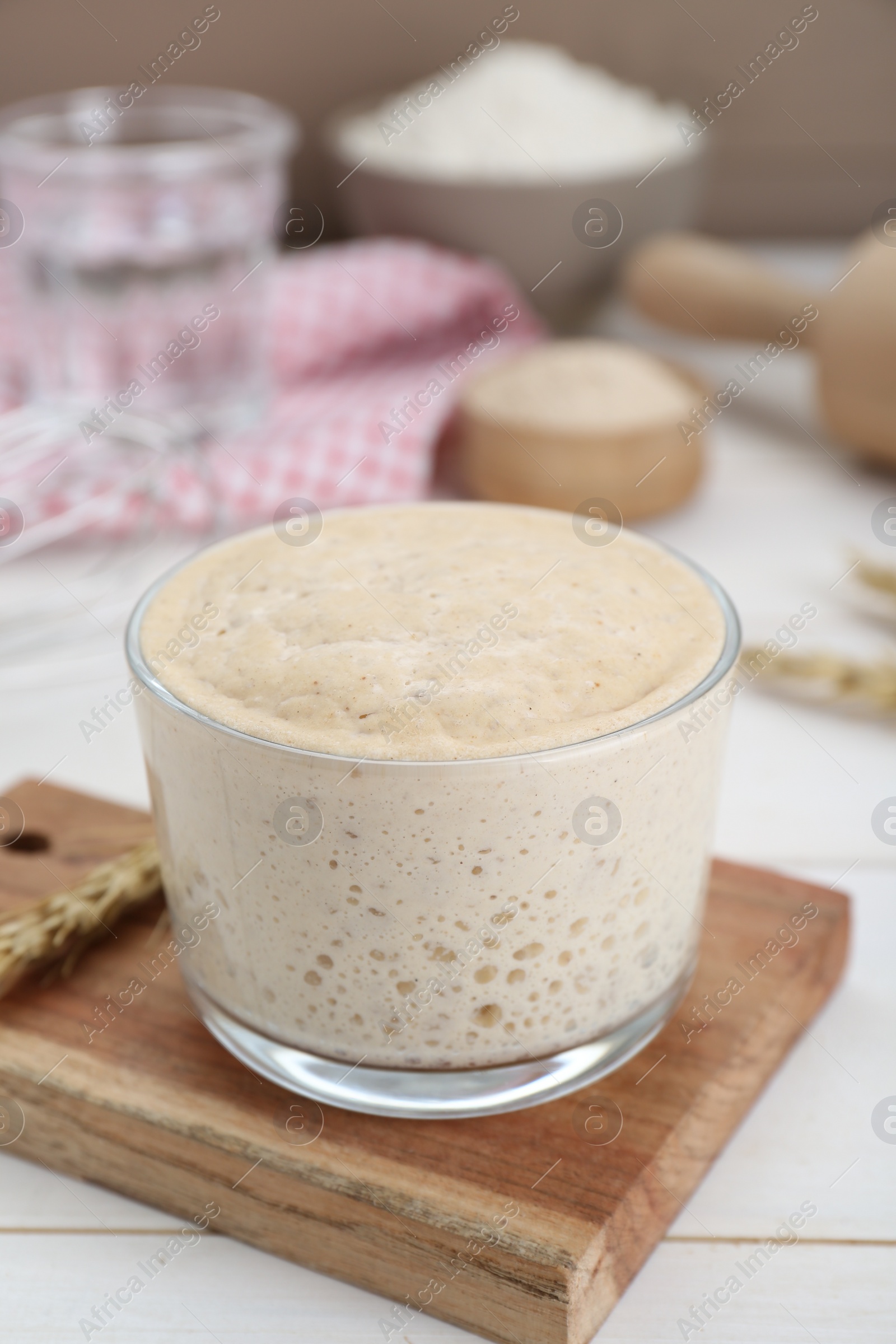 Photo of Leaven and ear of wheat on white wooden table