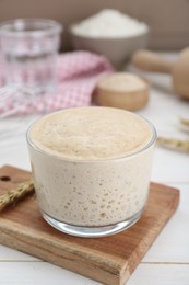 Leaven and ear of wheat on white wooden table