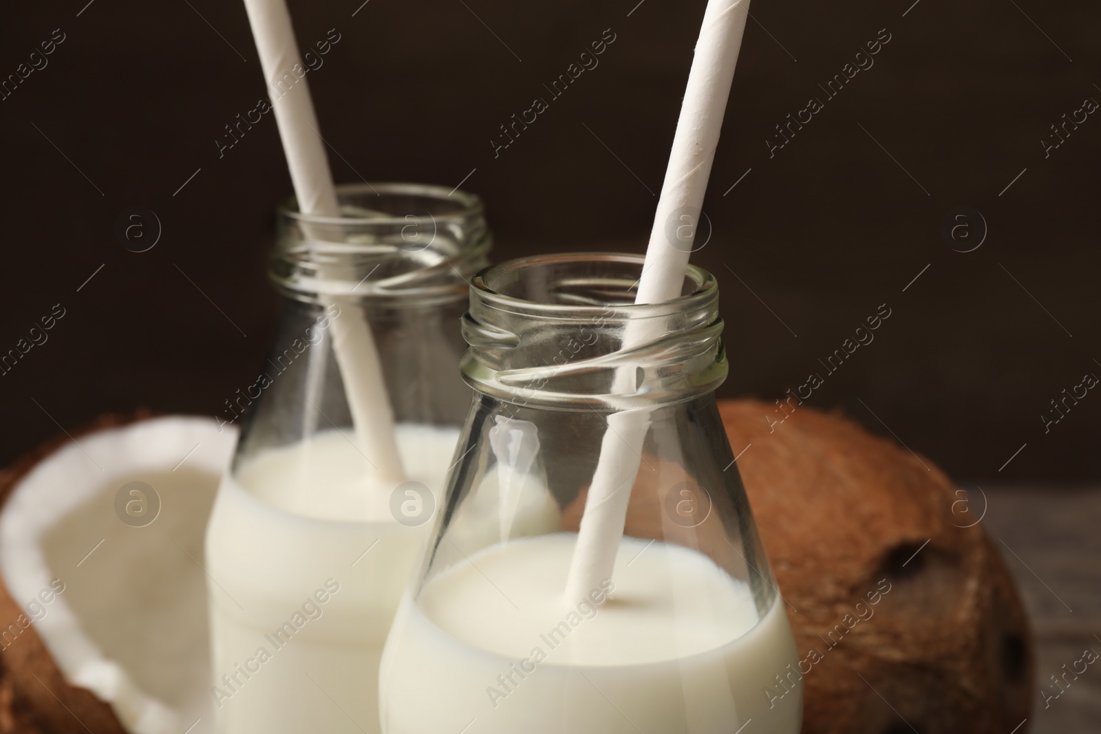Photo of Glass bottles of delicious coconut milk on table, closeup