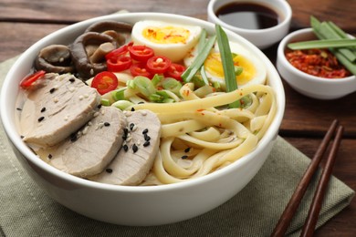 Delicious ramen with meat in bowl served on wooden table, closeup. Noodle soup