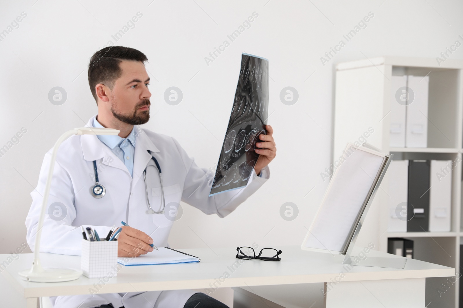 Photo of Orthopedist examining X-ray picture at desk in clinic