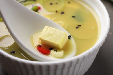 Eating delicious miso soup with tofu from bowl on table, closeup