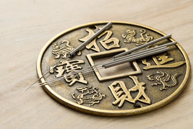 Photo of Acupuncture needles and ancient coin on beige marble table, closeup