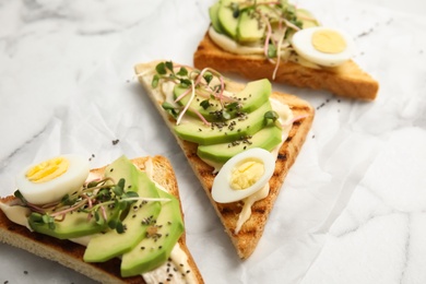 Photo of Tasty toasts with avocado, quail eggs and chia seeds on marble background