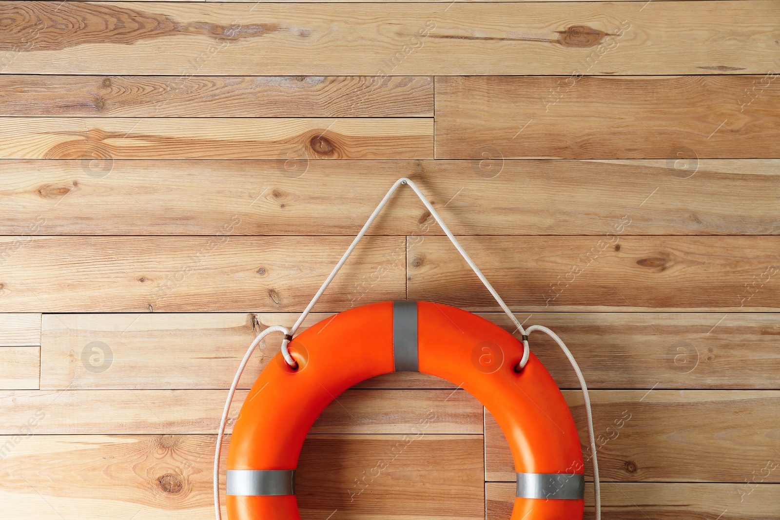 Photo of Orange lifebuoy and space for text on wooden background. Rescue equipment