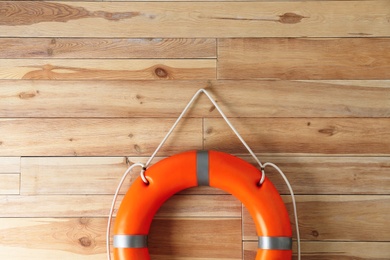 Photo of Orange lifebuoy and space for text on wooden background. Rescue equipment