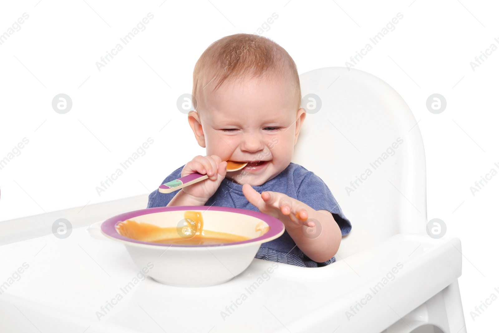 Photo of Adorable little child having breakfast in highchair against white background. Healthy baby food