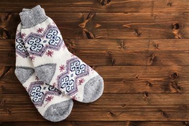 Photo of Knitted socks on wooden background, flat lay with space for text