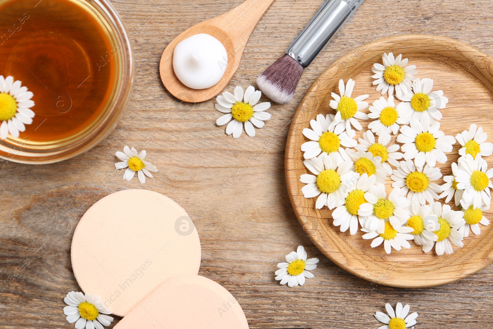 Photo of Flat lay composition with chamomile flowers and cosmetic products on wooden table