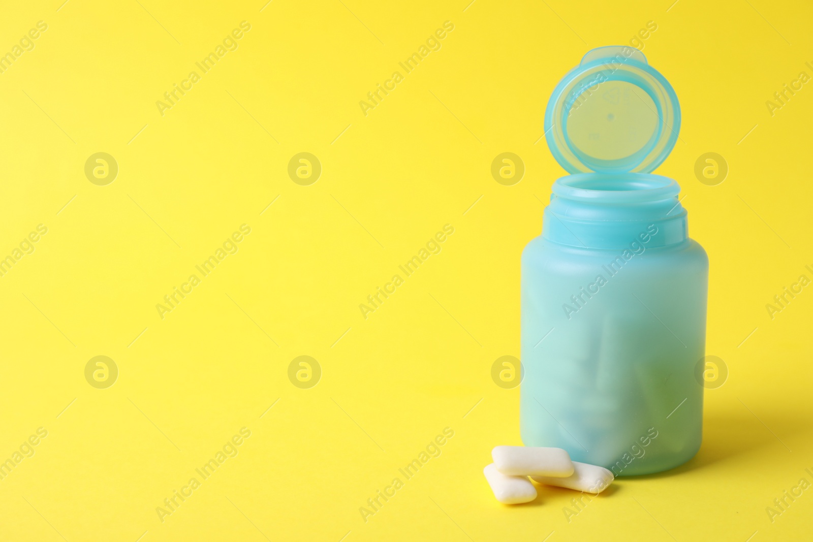 Photo of Jar with chewing gums on yellow background. Space for text