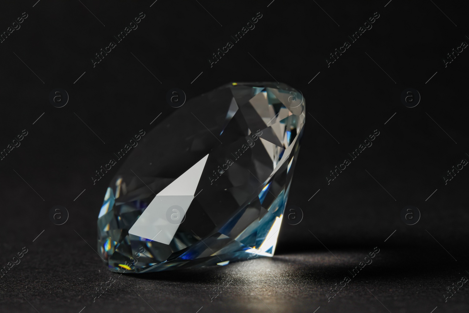 Photo of Beautiful dazzling diamond on dark background, closeup. Precious gemstone