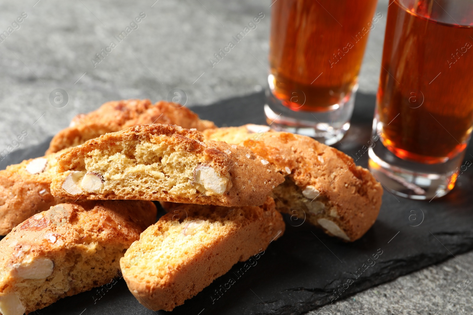 Photo of Tasty cantucci and glasses of liqueur on grey table, closeup. Traditional Italian almond biscuits