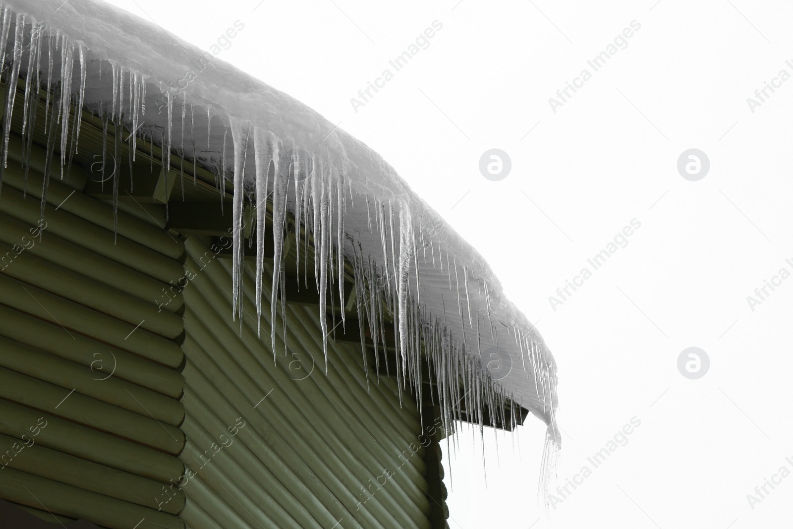 Photo of House with icicles on roof, low angle view. Winter season