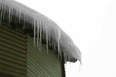 House with icicles on roof, low angle view. Winter season