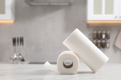 Photo of Rolls of paper towels on white marble table in kitchen. Space for text