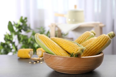 Photo of Bowl with tasty sweet corn cobs on table