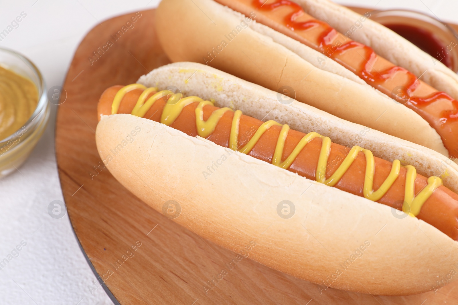 Photo of Tasty hot dogs with ketchup and mustard on white table, closeup