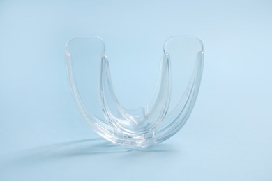 Photo of Dental mouth guard on light blue background, closeup. Bite correction