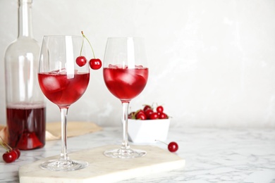 Photo of Delicious cherry wine with ripe juicy berries on white marble table. Space for text