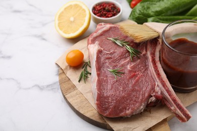 Photo of Raw meat, rosemary, marinade and products on white marble table, closeup. Space for text