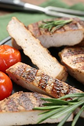 Cut grilled pork steak, rosemary and tomatoes on table, closeup