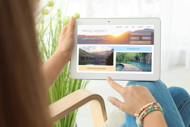 Young woman using tablet to plan trip, closeup. Travel agency website