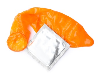 Unrolled orange condom and package on white background, top view. Safe sex