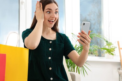 Special Promotion. Emotional woman looking at smartphone near window indoors