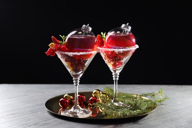 Creative presentation of Christmas Sangria cocktail in baubles and glasses on grey table against black background