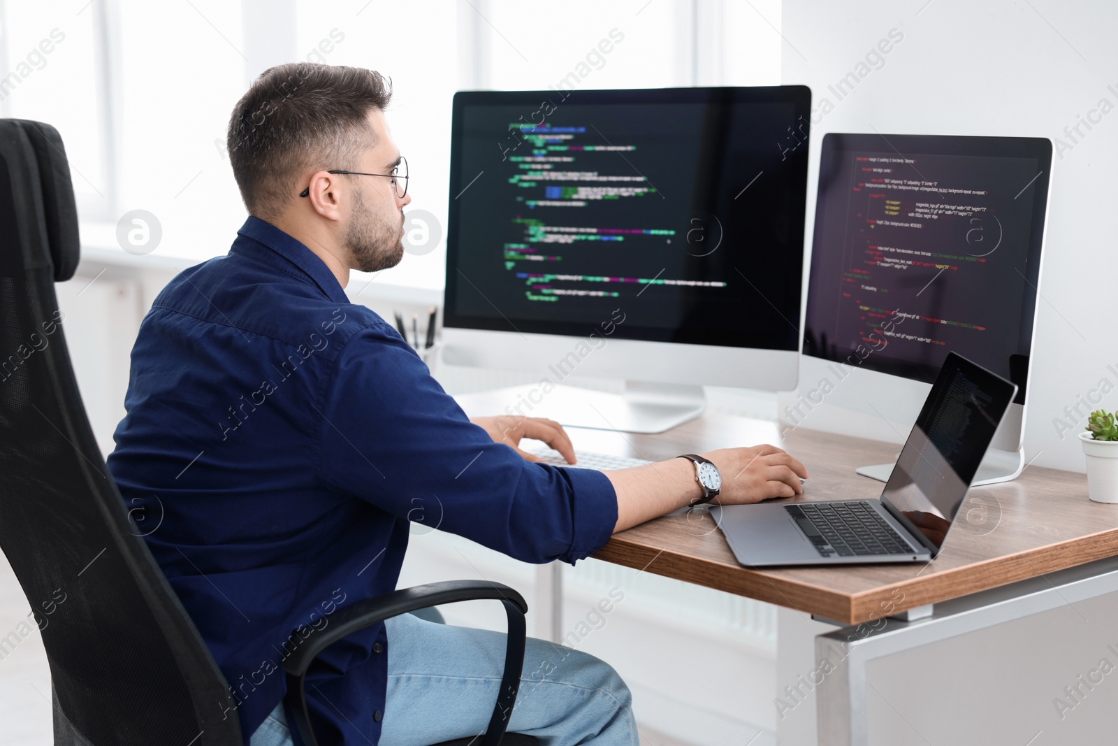 Photo of Young programmer working at desk in office