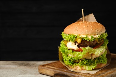 Photo of Burger with delicious patty on wooden table against dark background, space for text