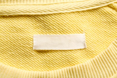 Blank clothing label on yellow sweater, top view