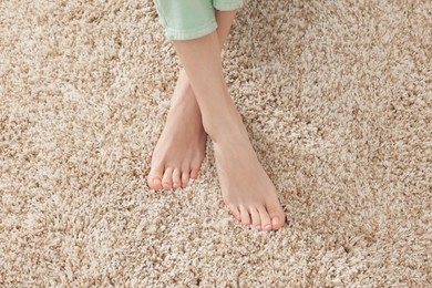 Woman on soft light brown carpet at home, above view