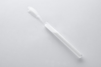 Photo of Glass tube with salt on white background, top view