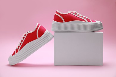 Photo of Stylish presentation of red classic old school sneakers on pink background