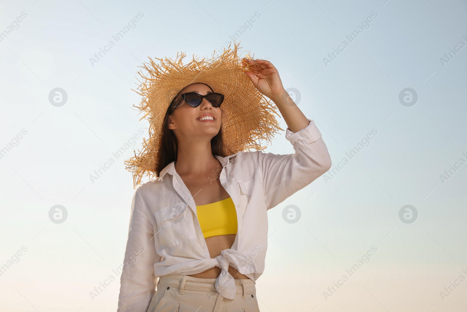 Photo of Young woman with sunglasses and hat against blue sky. Sun protection care