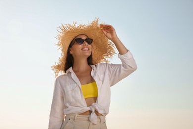 Photo of Young woman with sunglasses and hat against blue sky. Sun protection care