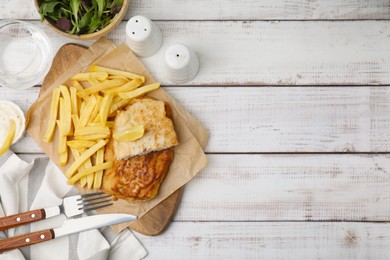 Photo of Tasty soda water battered fish, potato chips and lemon slice served on white wooden table, flat lay. Space for text