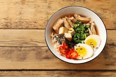 Photo of Noodle soup. Bowl of delicious ramen on wooden table, top view. Space for text