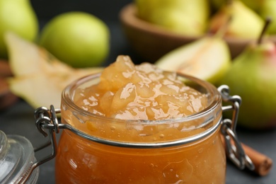 Photo of Tasty homemade pear jam on black table, closeup