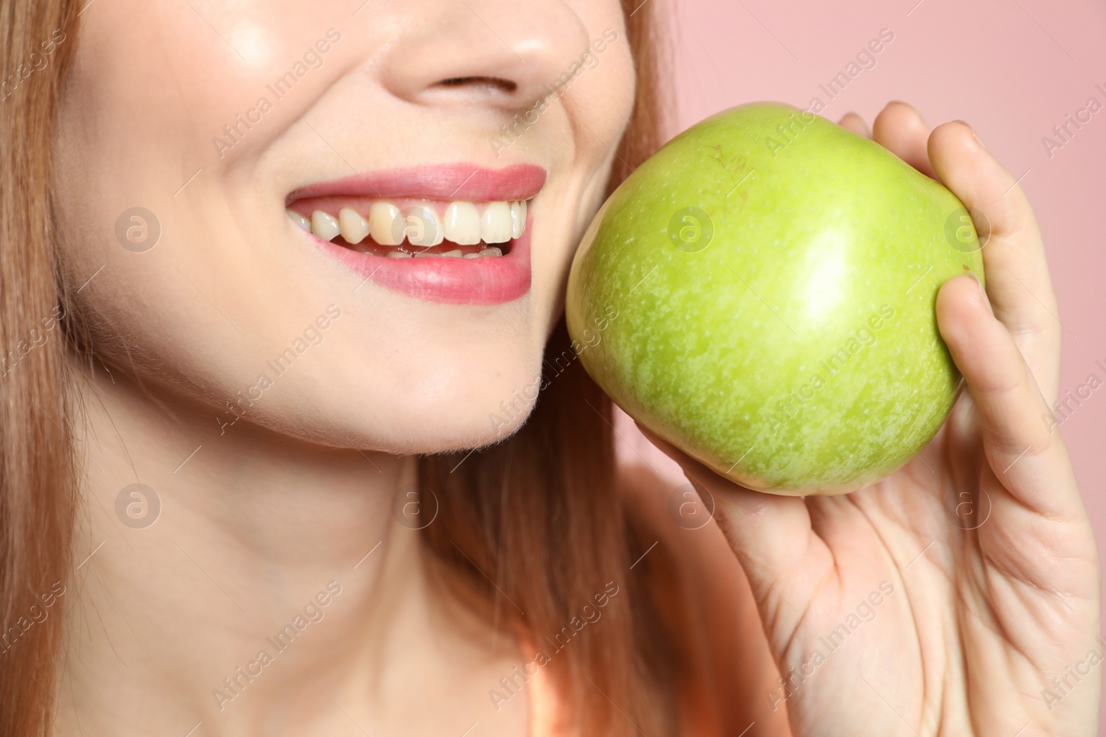 Photo of Smiling woman with perfect teeth and green apple on color background, closeup