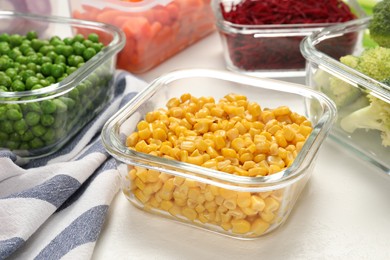 Photo of Containers with corn and fresh products on white table. Food storage