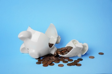 Broken piggy bank with coins on color background