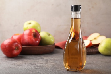 Photo of Composition with bottle of apple vinegar on table. Space for text