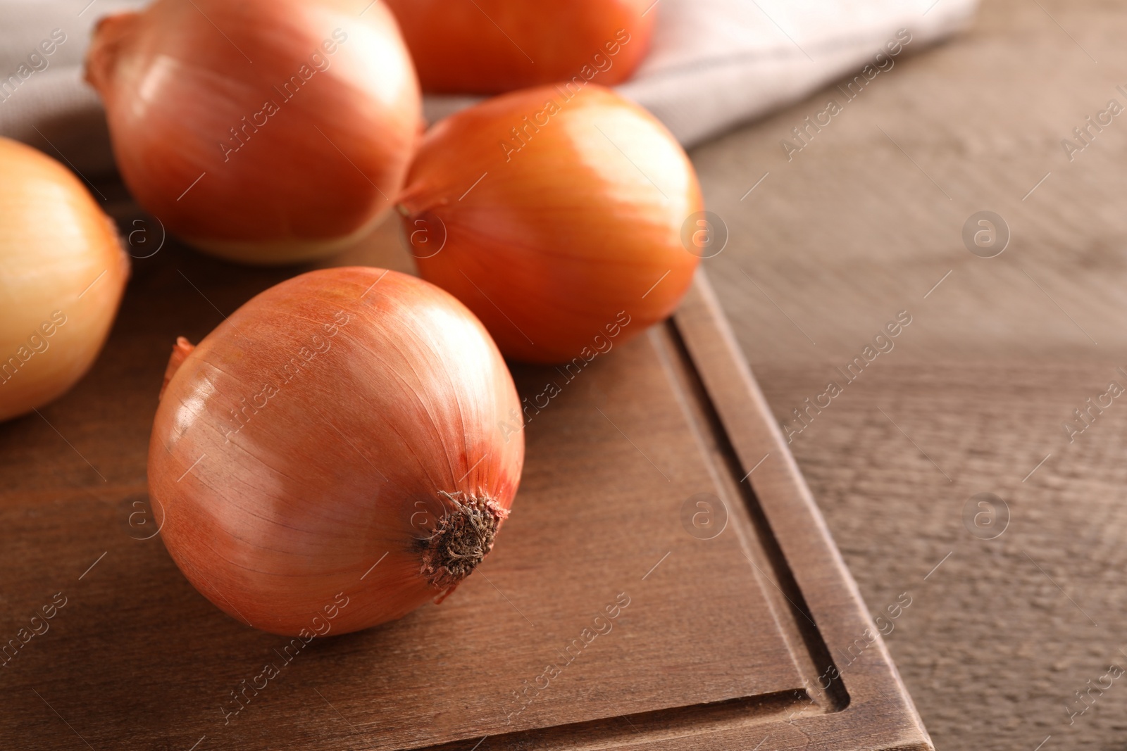 Photo of Many ripe onions on wooden table, closeup. Space for text