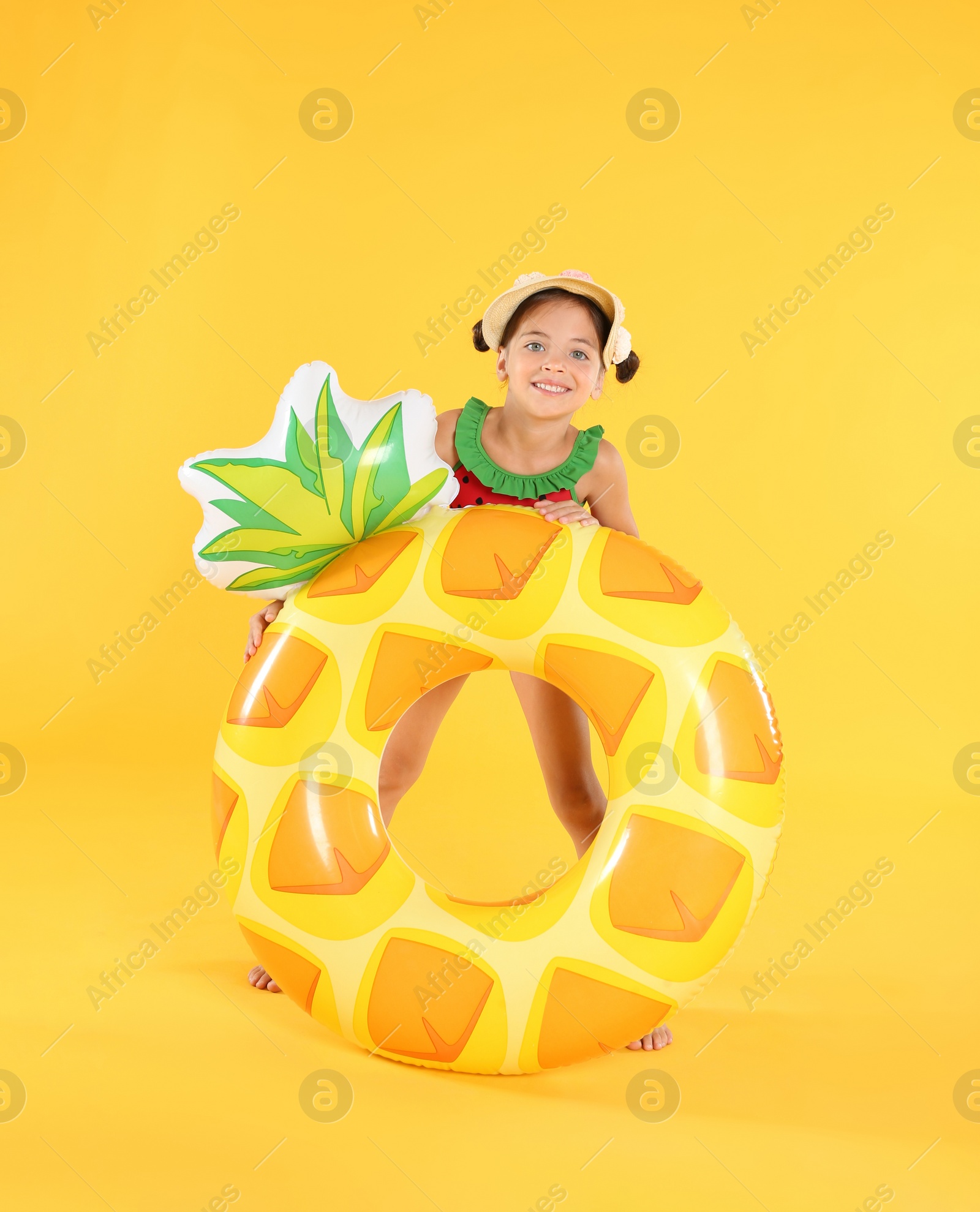 Photo of Cute little child in beachwear with bright inflatable ring on yellow background