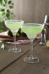 Photo of Delicious Margarita cocktail in glasses on wooden table, closeup