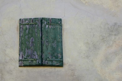 Photo of Window with old wooden shutters on concrete wall, low angle view